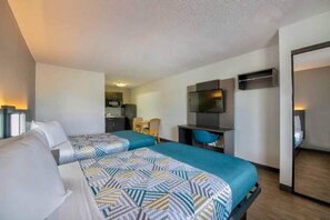 Een hotelkamer met twee bedden, een kitchenette, een televisie en een bureau.