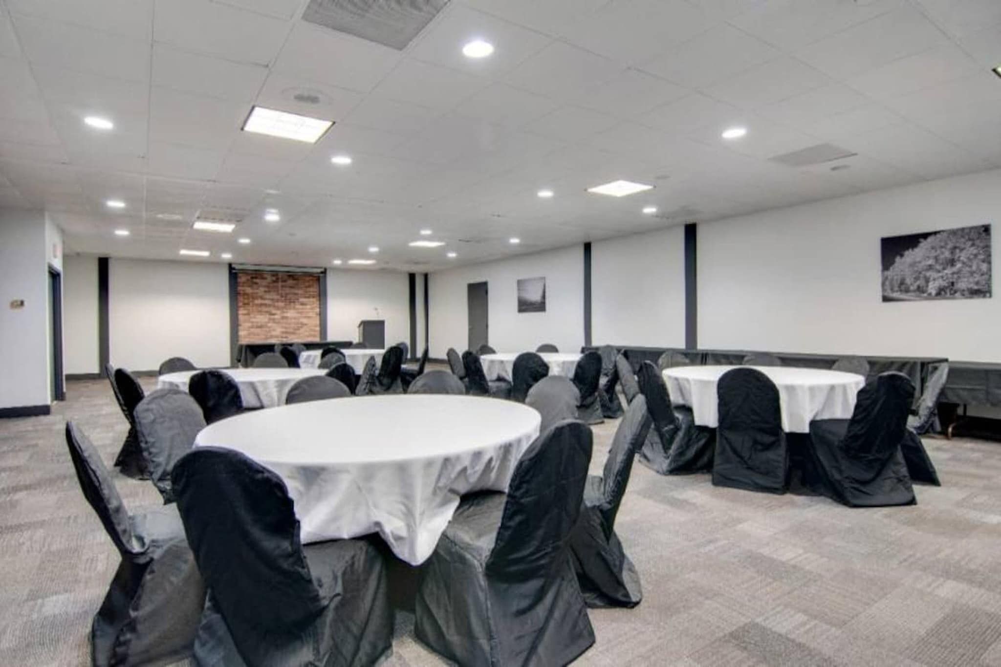 Une salle de conférence équipée de tables rondes, de chaises et d’un écran de projection.