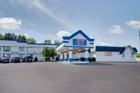 A 6-star hotel with a blue and white exterior, a parking lot, and a small adjacent building. - 1 Queen Bed|Non-Smoking, Micfridge (Clarion)