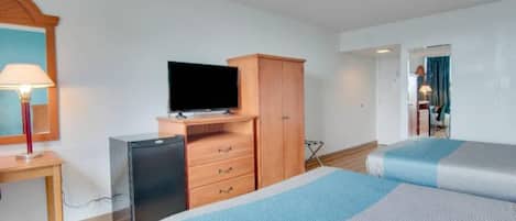 A hotel room with a bed, a desk with a lamp, a television, and a wardrobe.