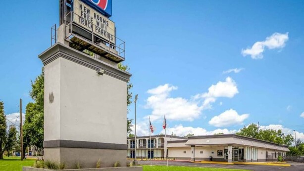 Un edificio con un letrero que anuncia habitaciones nuevas, WiFi gratuito y estacionamiento para camiones.