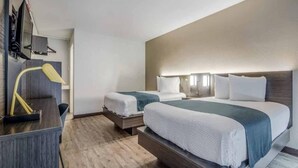 Una habitación de hotel con dos camas, un escritorio y una lámpara.