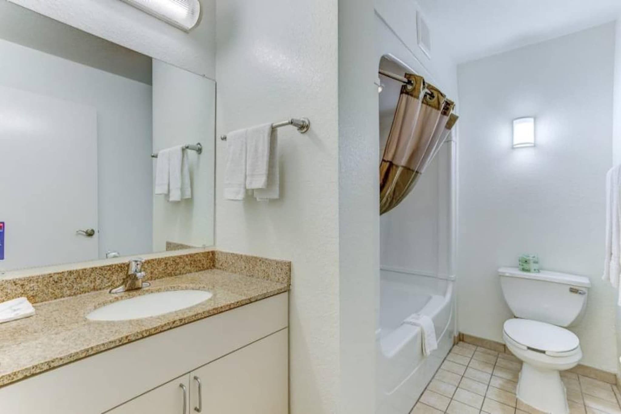 Une salle de bain équipée d’un lavabo, d’un miroir, d’une douche et de toilettes.