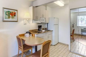 A compact kitchen with a dining table and chairs, a microwave, a coffee maker, and a refrigerator. - 2 Full Beds |Smoking|Kissimmee (Kissimmee)