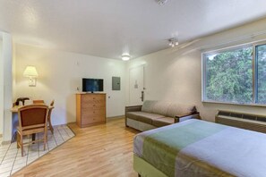 A room with a bed, a desk with a chair, a television, a dresser, and a window with a view of trees. - 2 Full Beds | Extended Suite (Kissimmee)