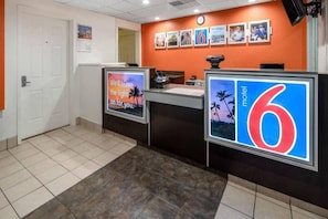 Un'area della reception con un bancone, una sveglia e una parete con quadri appesi.