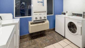 A laundry facility with a washing machine, dryer, and a soap and softener dispenser.