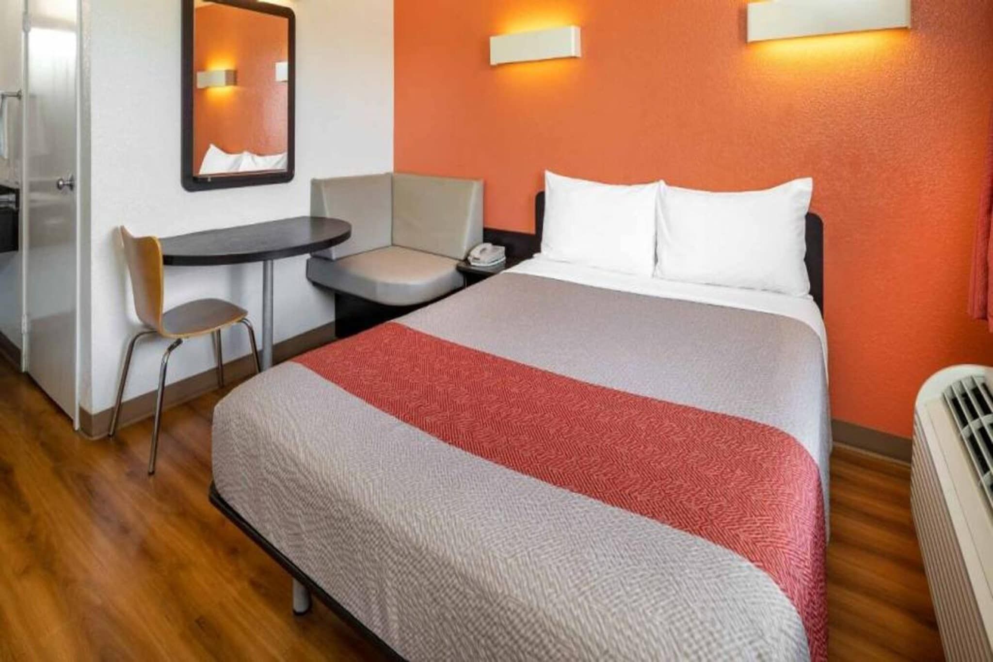 Een hotelkamer met een bed, een bureau, een stoel en een spiegel.