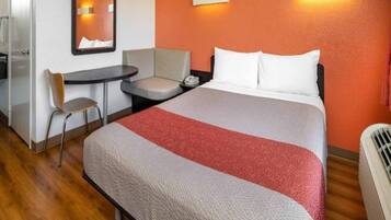 Een hotelkamer met een bed, een bureau, een stoel en een spiegel.