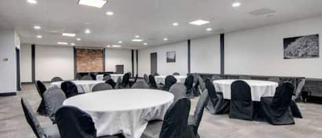 A conference room with round tables, chairs, and a projector screen.