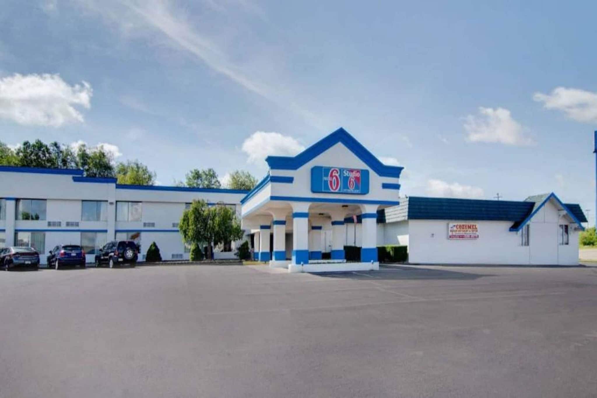 Un hôtel de luxe, classé six étoiles, avec une façade bleue et blanche, un parking et un petit bâtiment attenant.