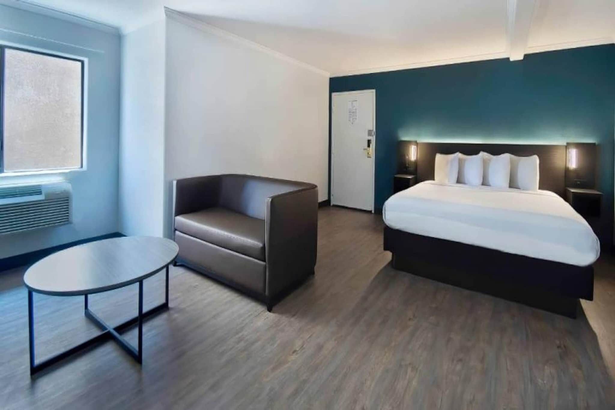 Una habitación de hotel moderna con una cama, un rincón de descanso y una mesita.