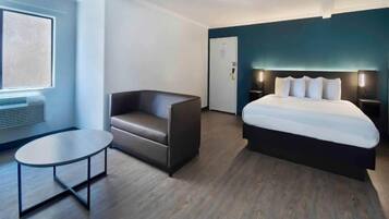 Una habitación de hotel moderna con una cama, un rincón de descanso y una mesita.