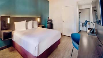 Una camera d'albergo con un letto, comodini, una scrivania con una sedia, uno specchio e una porta che dà su un'altra stanza.
