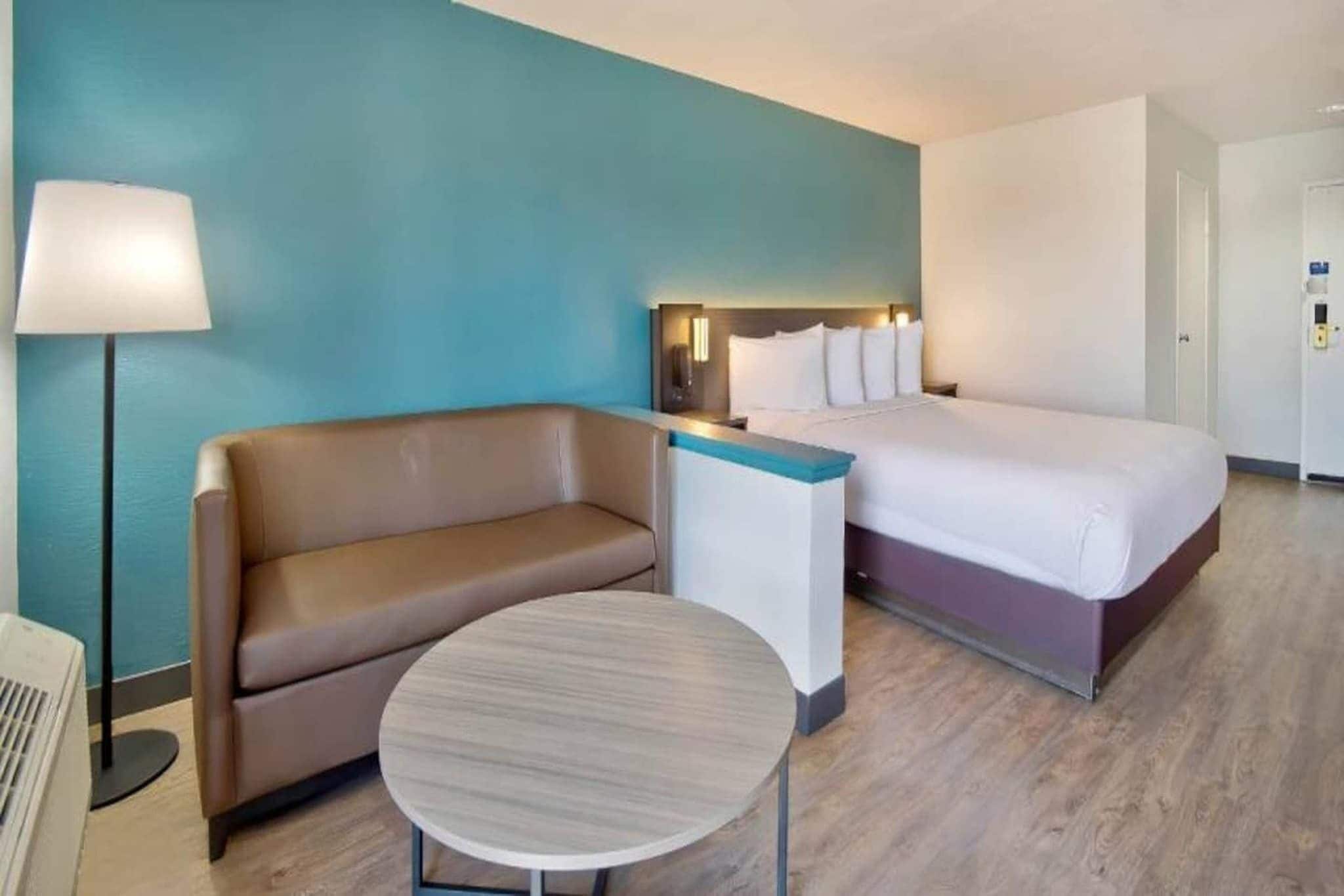 Ein Hotelzimmer mit einem Bett, einer Couch, einem kleinen Tisch und einer Lampe.
