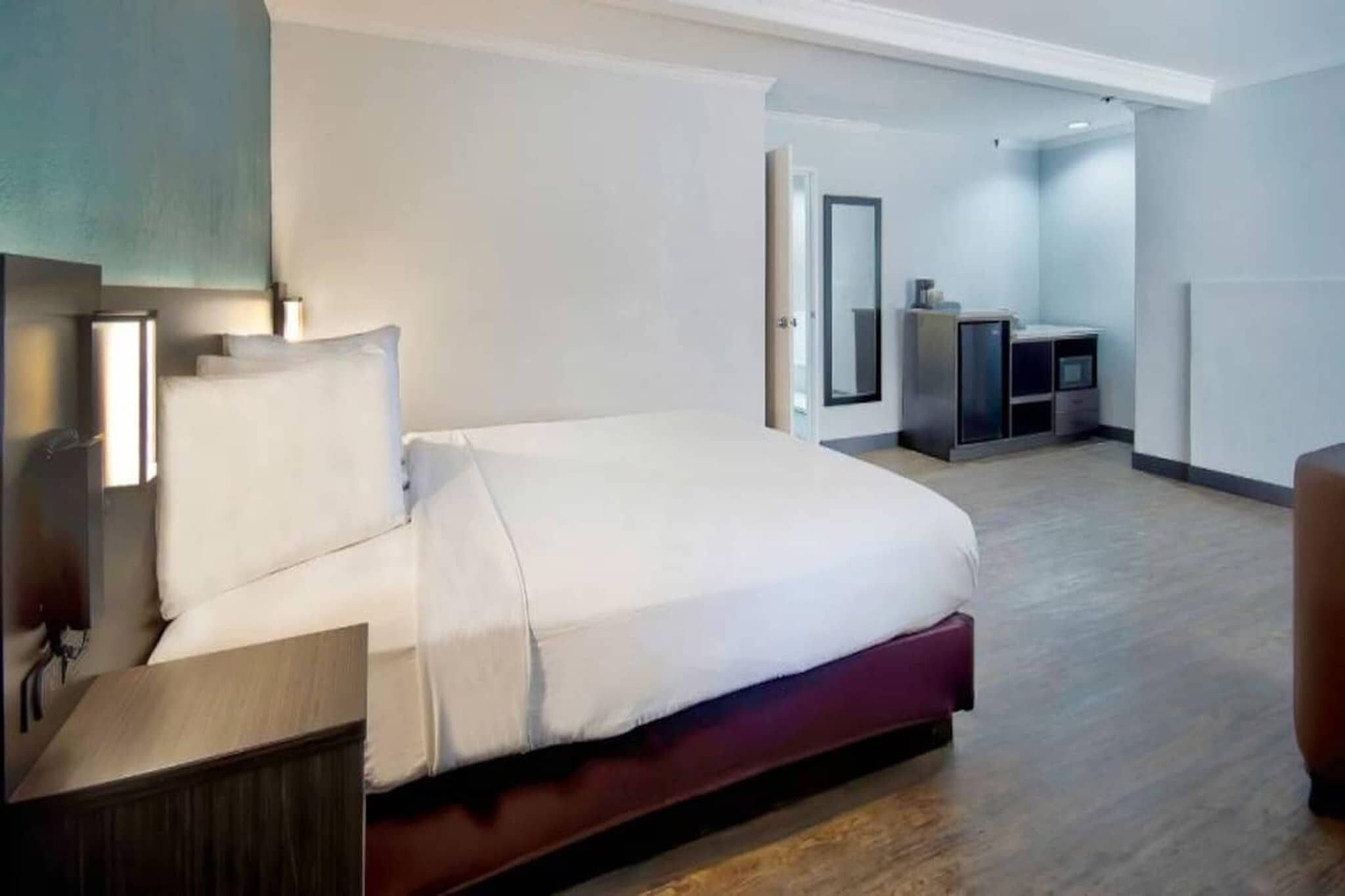 A modern hotel room with a large bed, bedside tables, a desk, and a wardrobe.