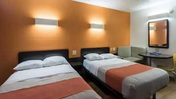 Una camera d'albergo con due letti singoli, un tavolino, una sedia e uno specchio a parete.