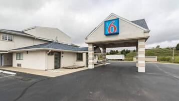 A motel with a prominent '6' sign, a covered parking area, and a building with a sloped roof.