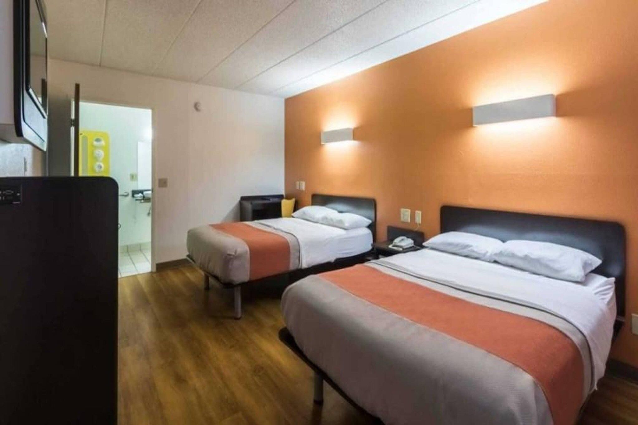 Ein Hotelzimmer mit zwei Betten, einem Schreibtisch und einem Kühlschrank.