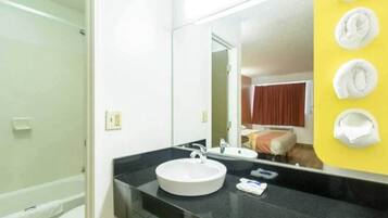 A bathroom with a round sink, a mirror, and a yellow towel rack.