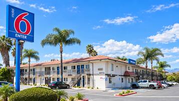 A motel with a red roof, palm trees, and a blue '6 Enter' sign.