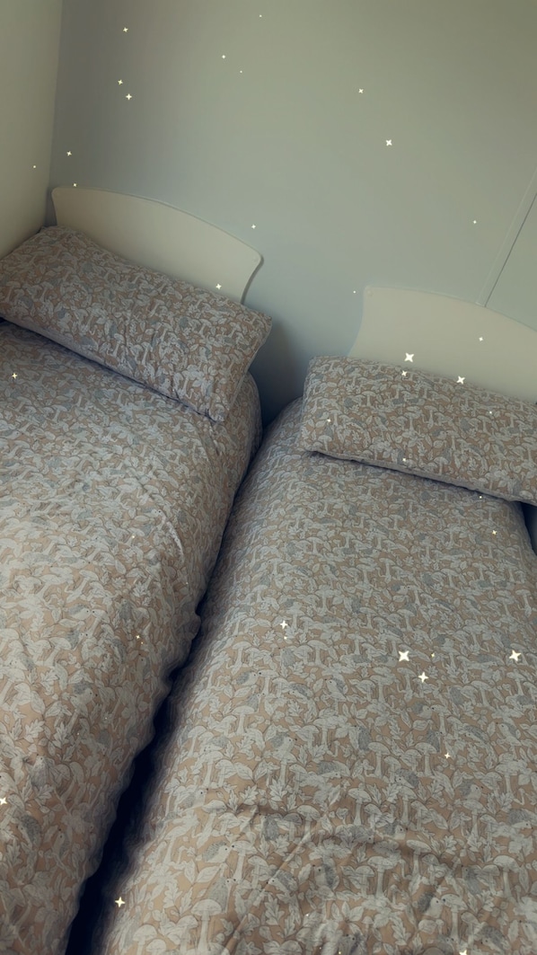 Two beds with floral patterned bedding and white headboards in a room.