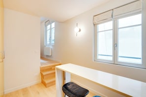 Une pièce avec un escalier en bois, un bureau blanc et une fenêtre donnant sur un beau paysage.