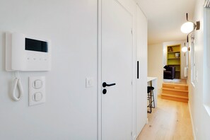 Un couloir avec une porte blanche, un thermostat et un téléphone.