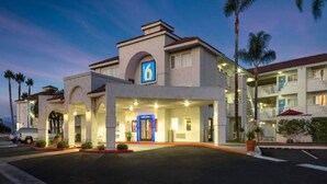Hotel com um grande letreiro '6', entrada convidativa e área externa coberta.