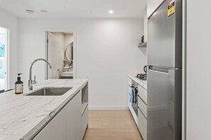 Una cuina moderna amb taulell de marbre, electrodomèstics d'acer inoxidable i sòl de fusta.