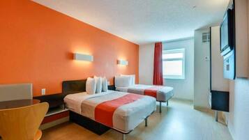 A hotel room with two beds, a desk, a chair, and a television.