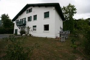 A two-story building with a balcony, a small garden, and a wooden fence.