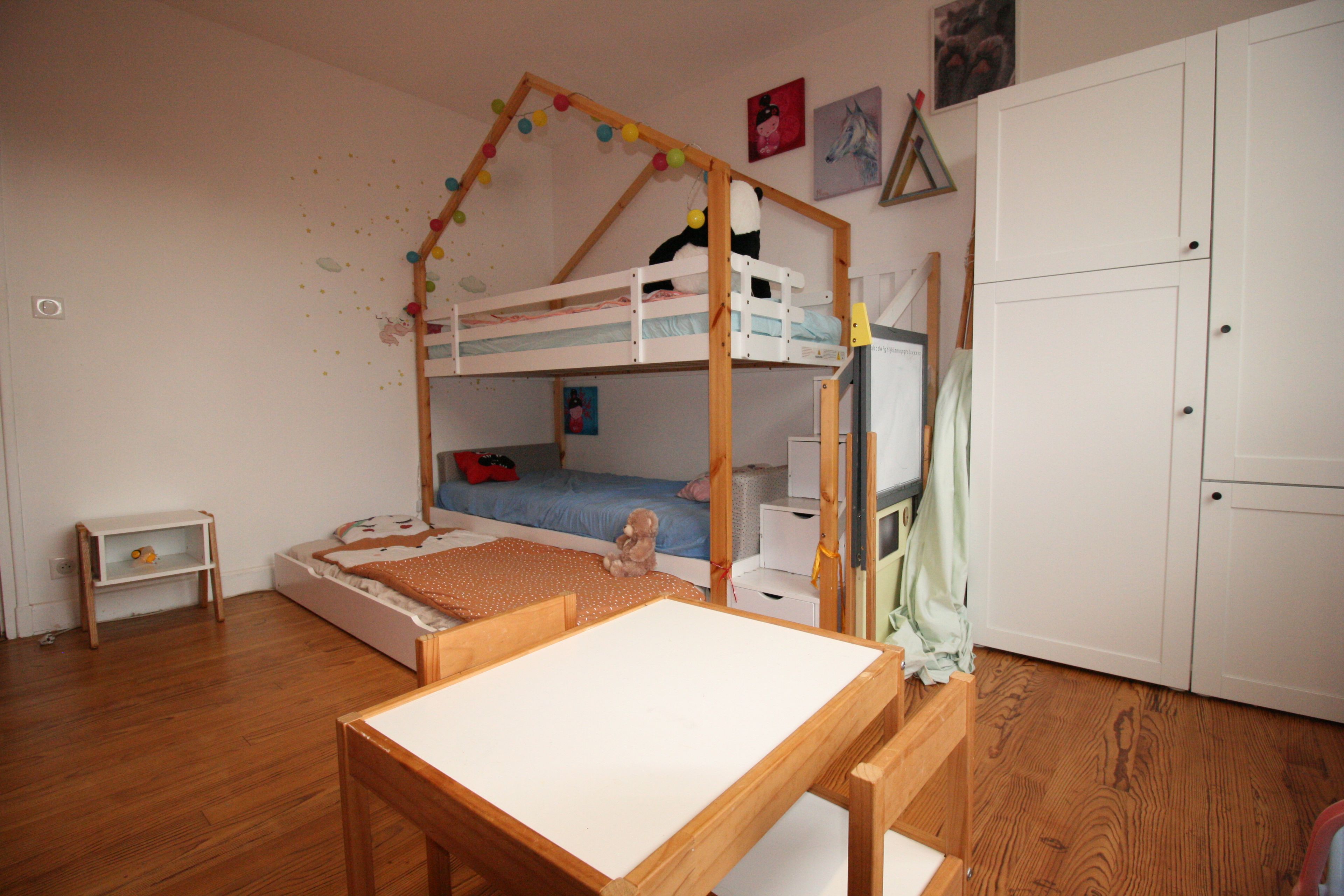 A child's bunk bed room with a desk and a wardrobe.