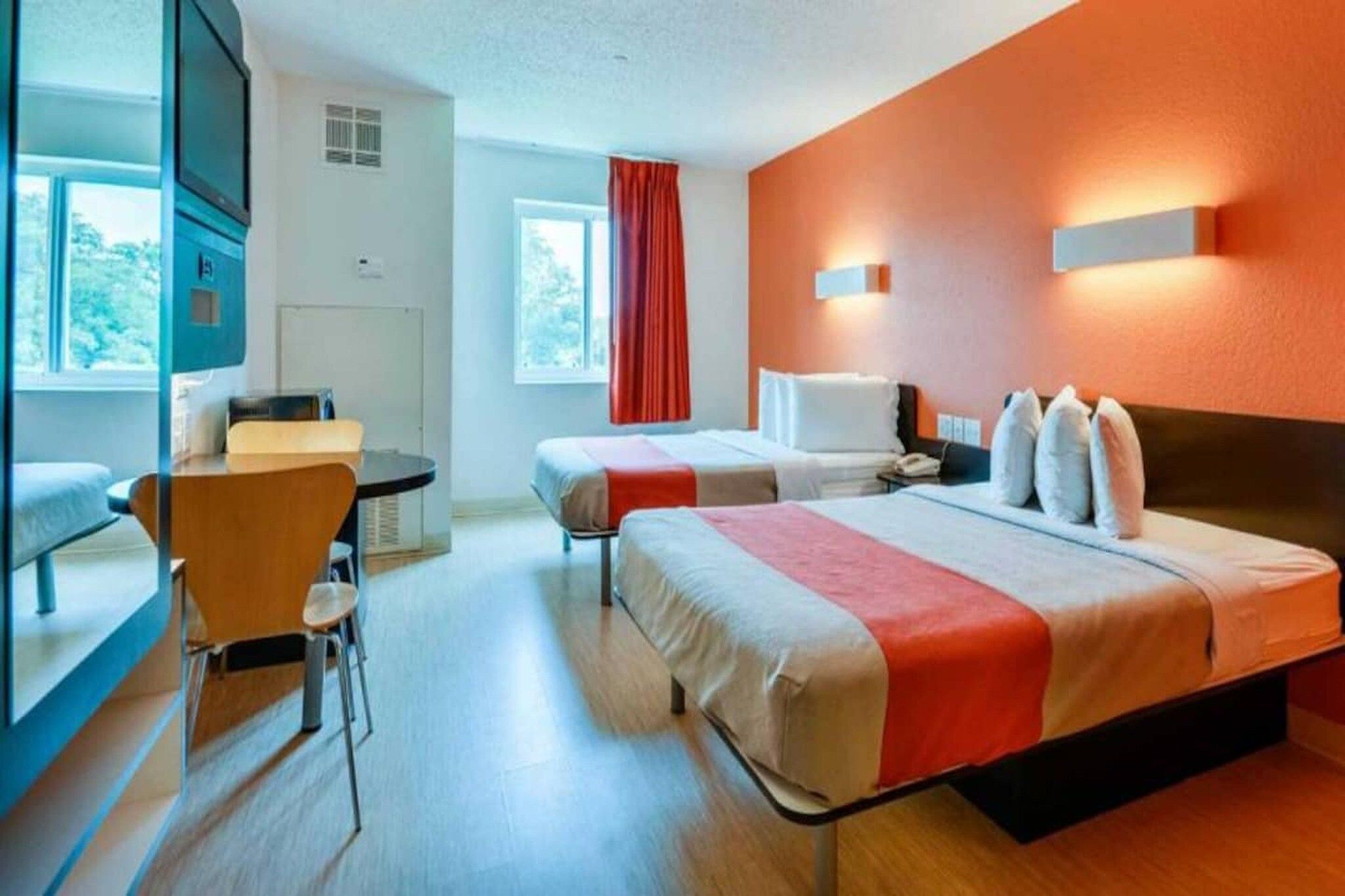 Une chambre d’hôtel avec un lit, un bureau, une chaise et une fenêtre.