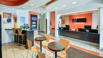 A hotel lobby with a reception desk, seating area, and a digital information kiosk.