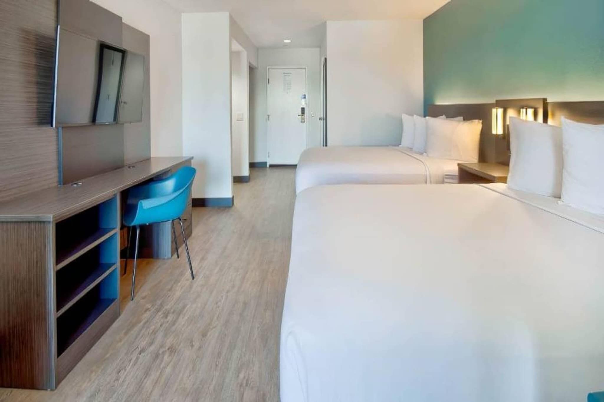 Una habitación de hotel con cama, escritorio, silla y televisor.