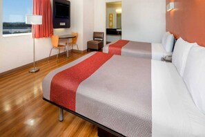 Een hotelkamer met twee bedden, een bureau, een stoel, een televisie en een raam met uitzicht.