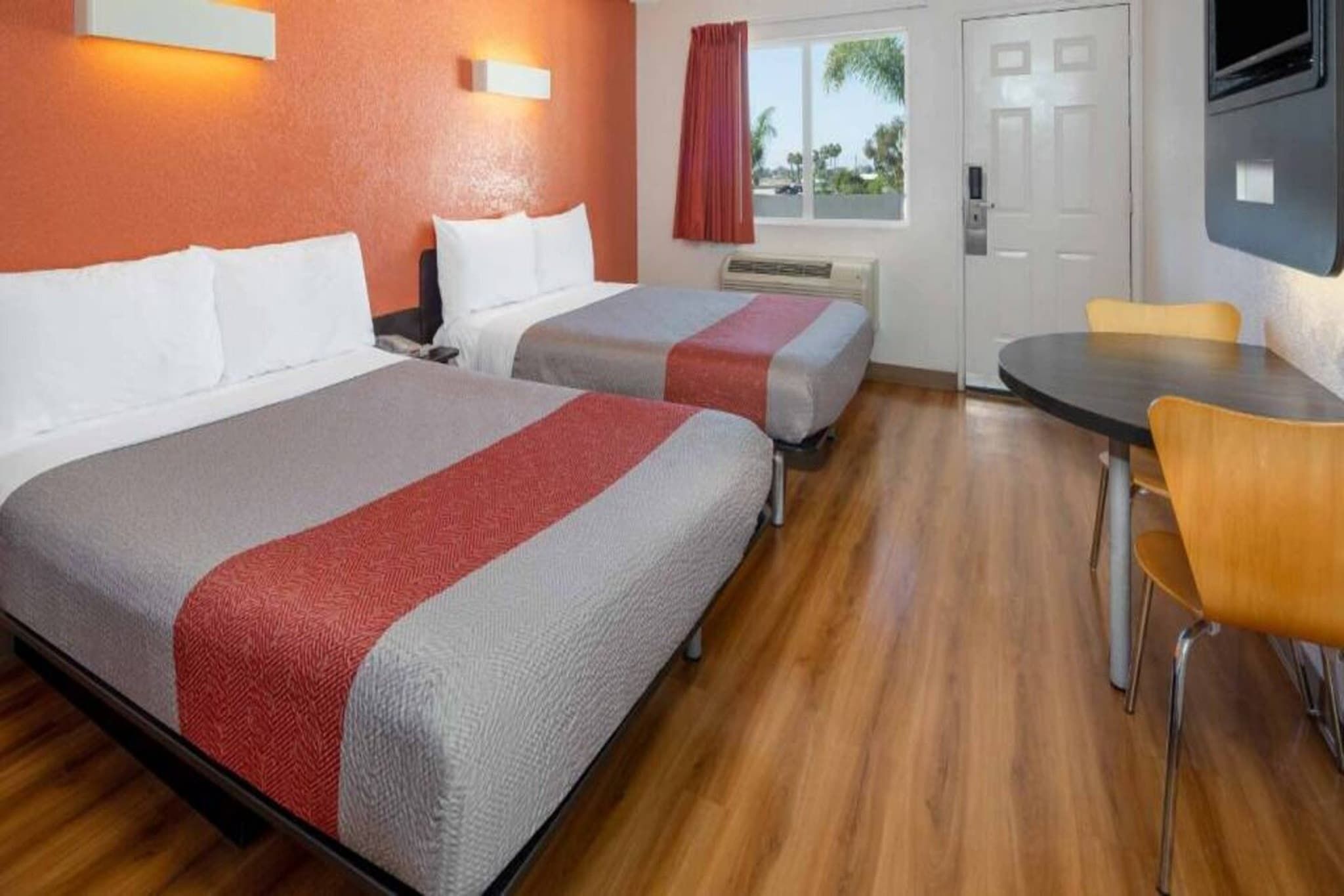 Una habitación de hotel con dos camas, una mesa de comedor y un televisor.