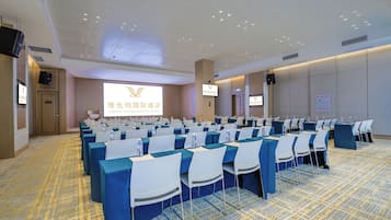 A conference room with rows of tables and chairs, a projection screen, and a sign indicating the Vienna International Hotel.