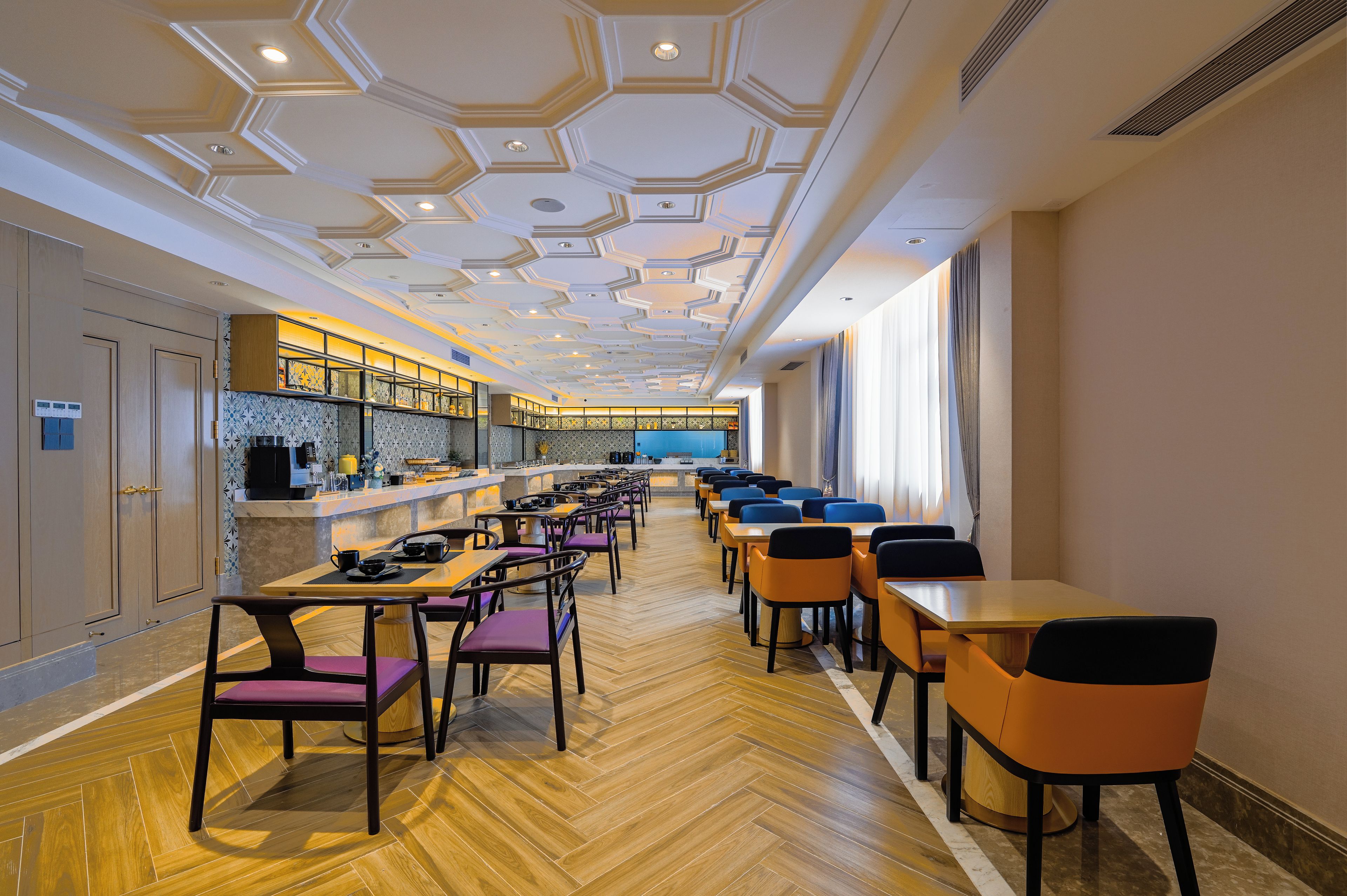 Un restaurante moderno con diseño de techo hexagonal, suelo de madera y una larga barra con asientos.