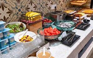 Un bufé con diversas opciones de comida, incluyendo frutas, verduras y salsas.