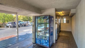 A vending machine with various items, a parking lot with vehicles, and a building entrance.