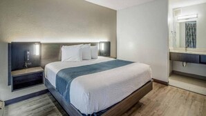 A hotel room with a bed, bedside tables, a mirror, and a nightstand. - 1 King Bed | Non-Smoking, Micfridge (Groves)
