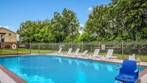 A swimming pool with a fenced area, lounge chairs, and a building in the background. - 1 King Bed | Non-Smoking, Micfridge (Groves)