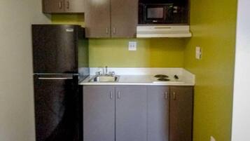 A compact kitchen with a refrigerator, sink, and microwave.