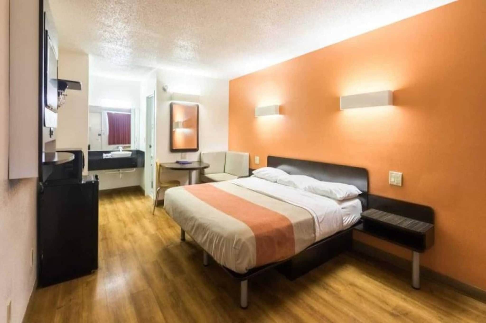 Una habitación de hotel con cama, mesita de noche y un pequeño escritorio con silla.