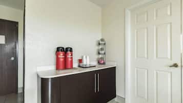 A hallway with a white door, a dark brown cabinet, and a small shelf with red containers and a white tray.