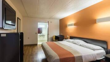 Une chambre d’hôtel comprenant un lit, un bureau, une chaise, un miroir et un téléviseur.