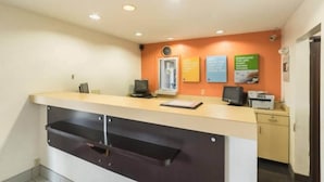 Una recepción con una computadora, una impresora y un reloj en la pared.