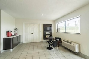 A room with a kitchenette, a dining area, and a large window.